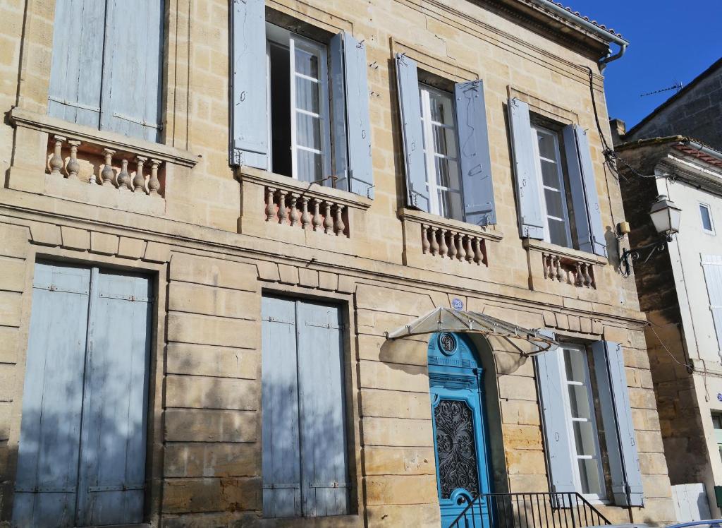 un edificio antiguo con una puerta y ventanas azules en Maison de Maître Elegia, en Castillon-la-Bataille