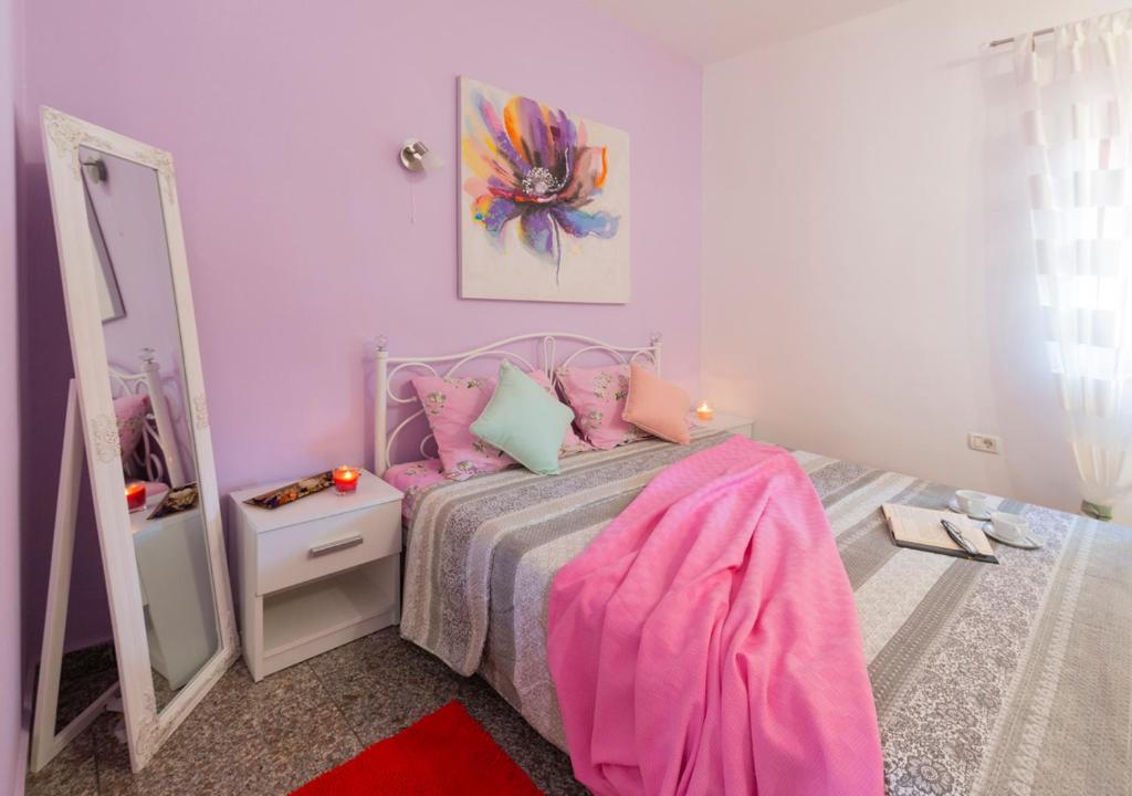 - une chambre rose avec un lit et un miroir dans l'établissement Lavanda, à Umag