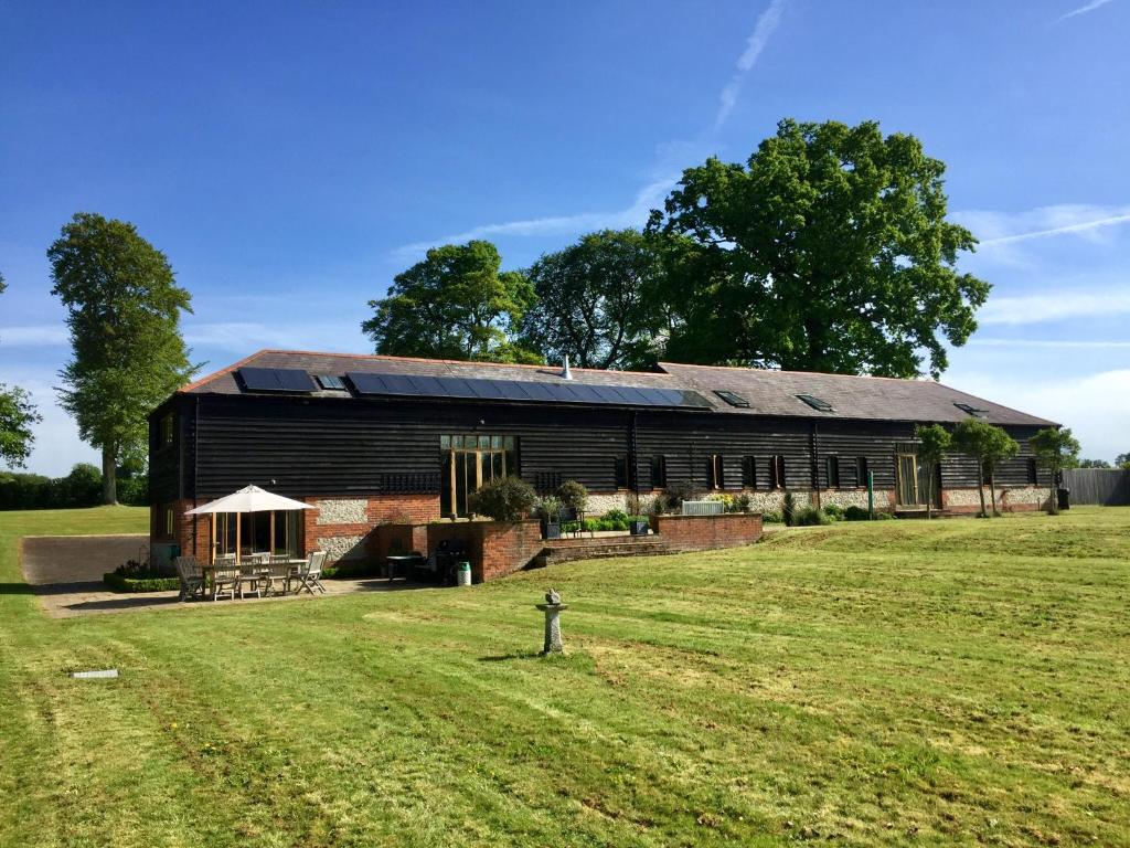 a barn with a grass field in front of it at Mulberry Barn in Micheldever