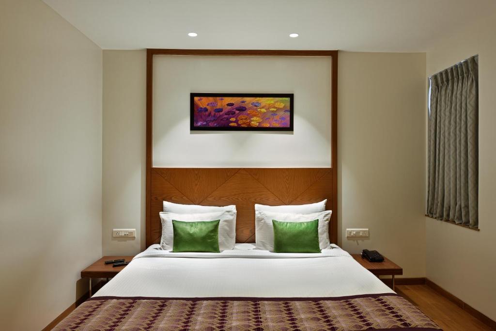 Un dormitorio con una cama con dos almohadas verdes. en Hotel Leafio Marigold-Near Airport, en Bombay