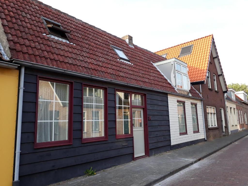 a black building with a red roof on a street at Het Zwaantje in Serooskerke