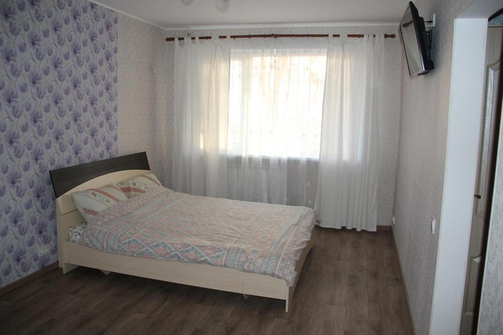Habitación pequeña con cama y ventana en Современная 1-комнатная квартира en Járkov