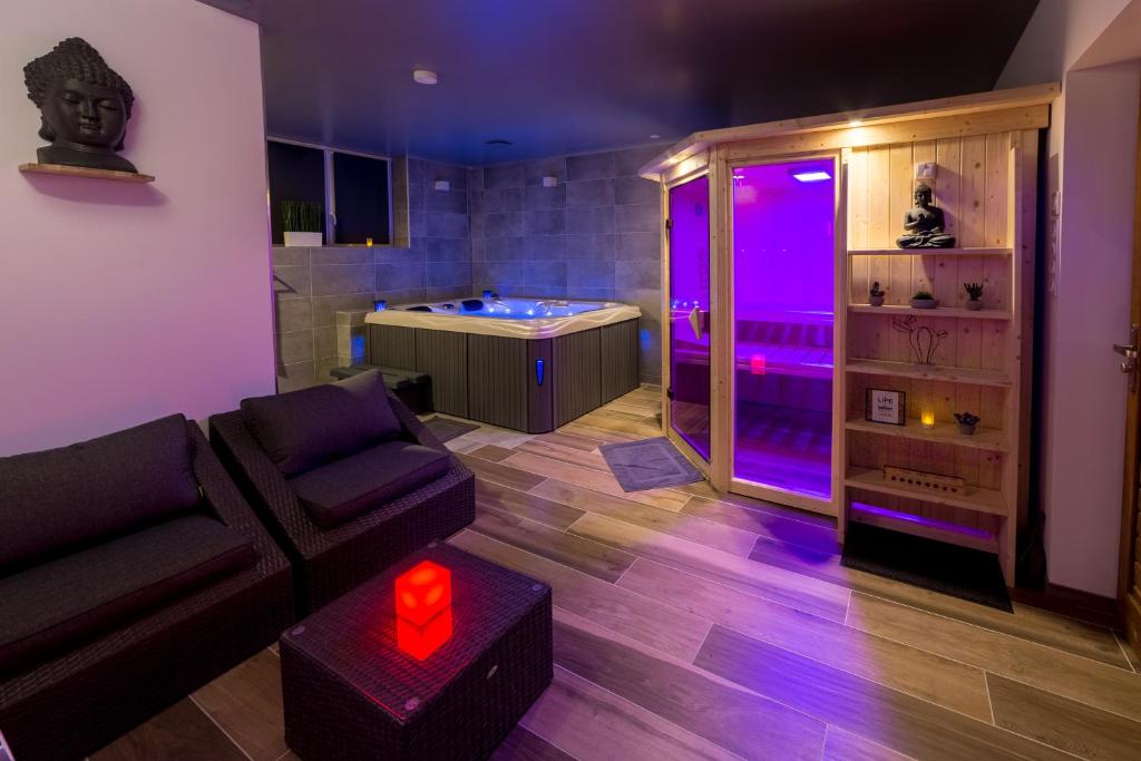 sala de estar con sofá y bañera con luces moradas en Autrement Spa, en Avelin