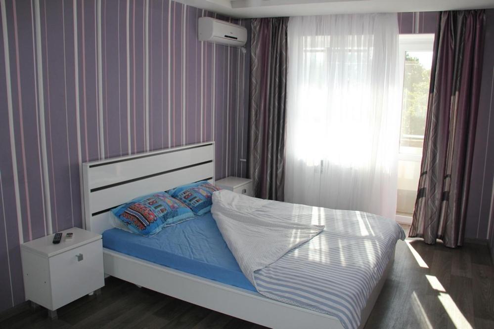 sypialnia z łóżkiem z niebieską pościelą i oknem w obiekcie Современная 1-комнатная квартира w Charkowie