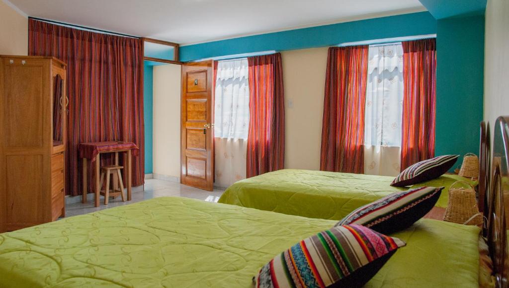 um quarto com 2 camas verdes e cortinas vermelhas em B&B Valcava em Urubamba