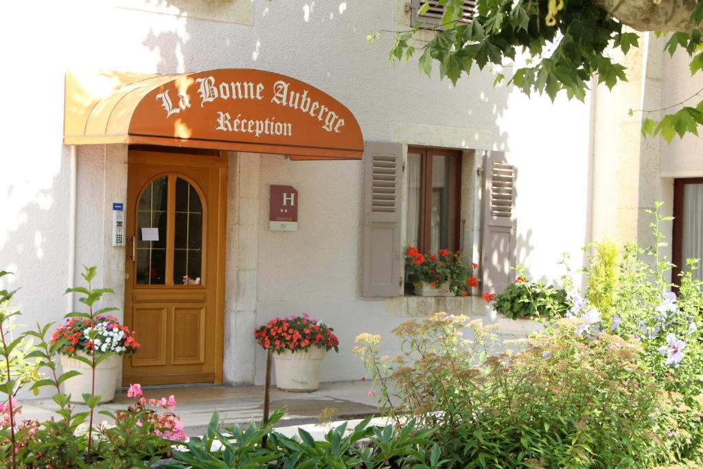 un edificio con un cartel para una floristería en La Bonne Auberge, en Ségny