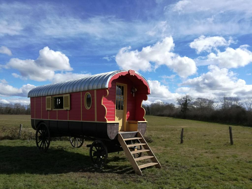 a red train car sitting in a field at La Roulotte des Grillots in Beaulon