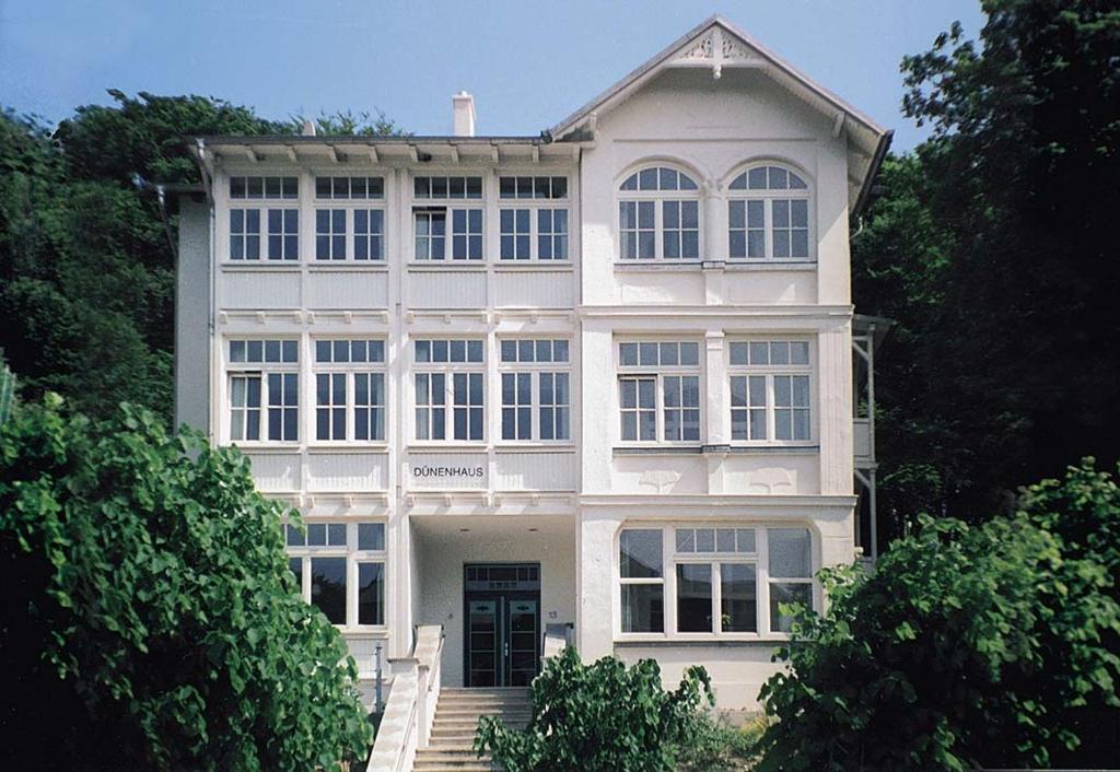 una gran casa blanca con una puerta delantera y árboles en Dünenhaus Sellin, en Ostseebad Sellin