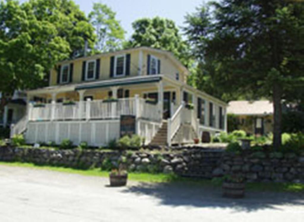 a large yellow house with a stone wall at Serendipity B&B in North Hatley