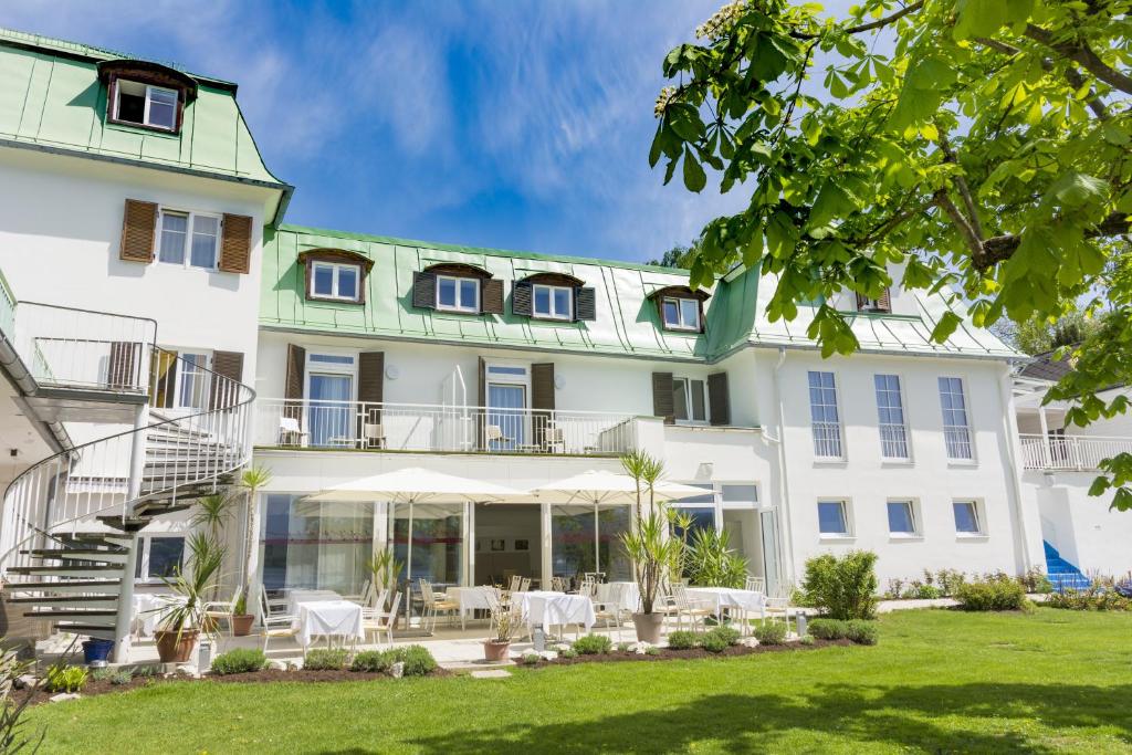 eine Außenansicht eines Gebäudes mit Rasen in der Unterkunft Strandhotel Kärntnerhof in Pörtschach am Wörthersee