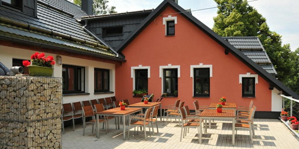 une terrasse avec des tables et des chaises en face d'une maison dans l'établissement Penzion Lazy Daisy, à Janov nad Nisou