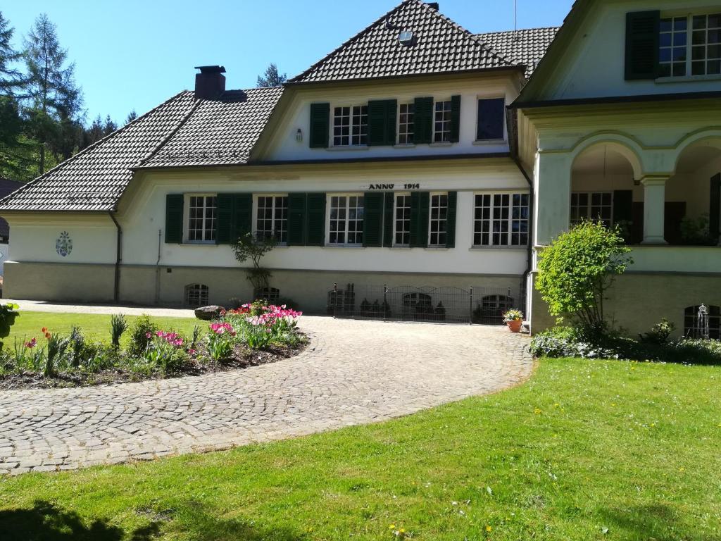 a house with a cobblestone driveway in front of it at Gutshaus Wilhelmsruh in Möhnesee