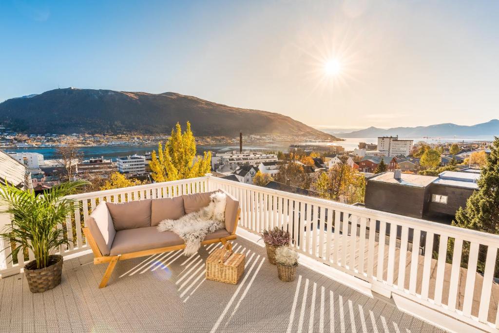a couch on a balcony with a view of a city at BraMy Apartments The LUX View in Tromsø