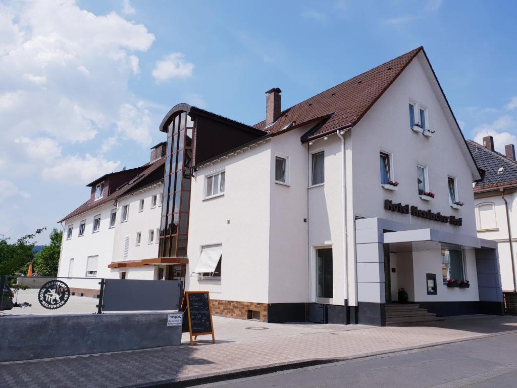 een wit gebouw met een bord ervoor bij Hotel Hessischer Hof in Melsungen