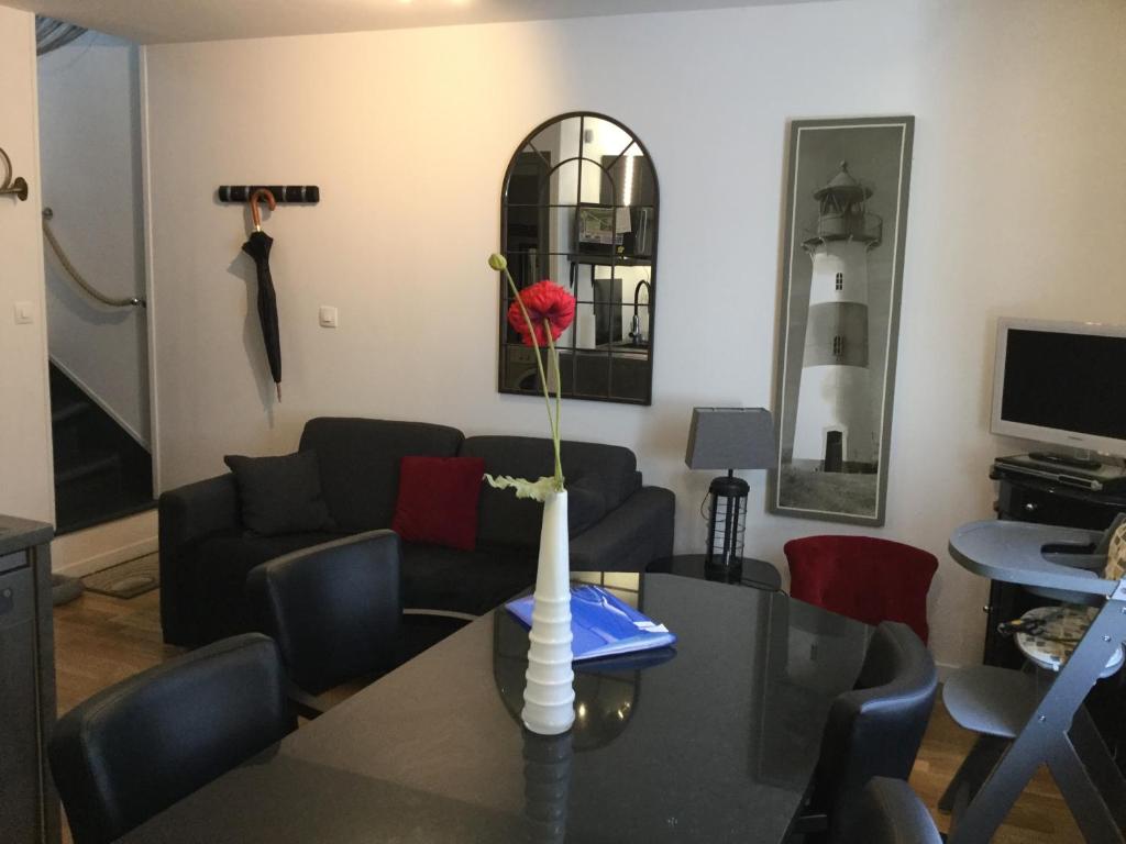 uma sala de estar com uma mesa com uma flor vermelha num vaso em Maison de pêcheur em Cancale