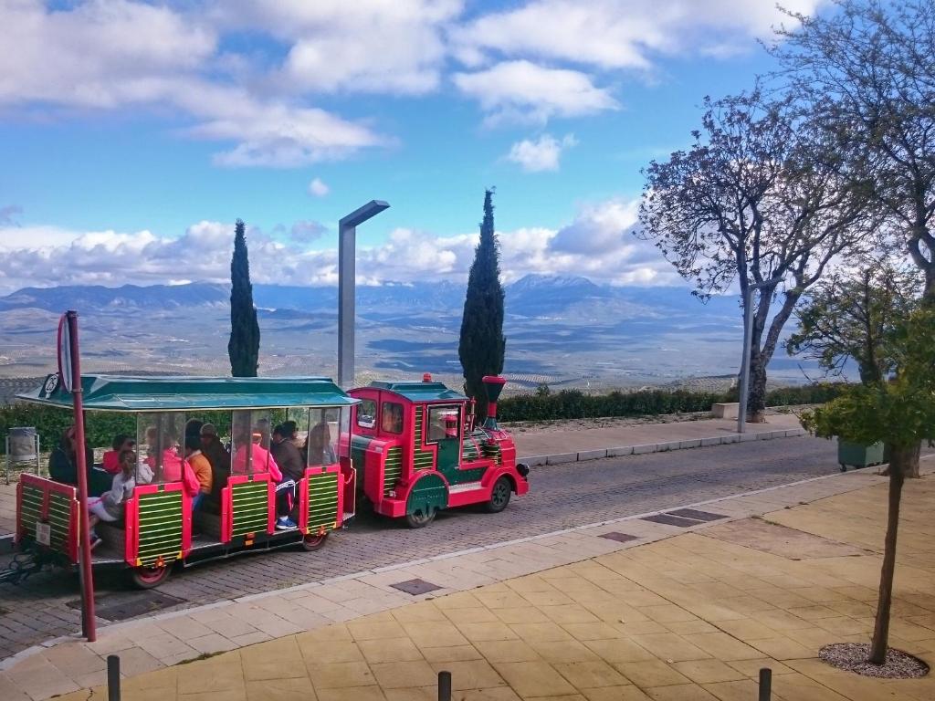 a red and green train with people riding at "Ventana del Guadalquivir " in Baeza