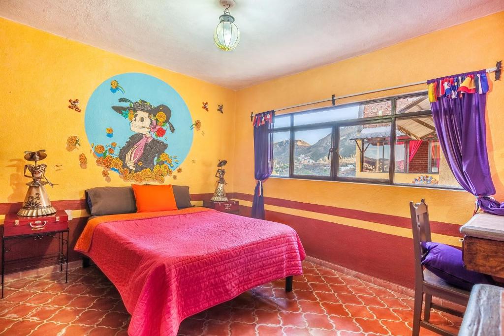 1 dormitorio con 1 cama y una pintura en la pared en Hostal Casa de Dante en Guanajuato
