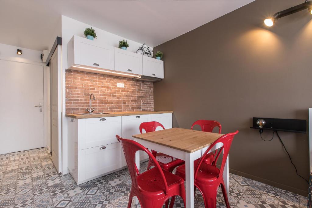 uma cozinha com uma mesa de madeira e cadeiras vermelhas em Studio Air d'été em Roquebrune-Cap-Martin