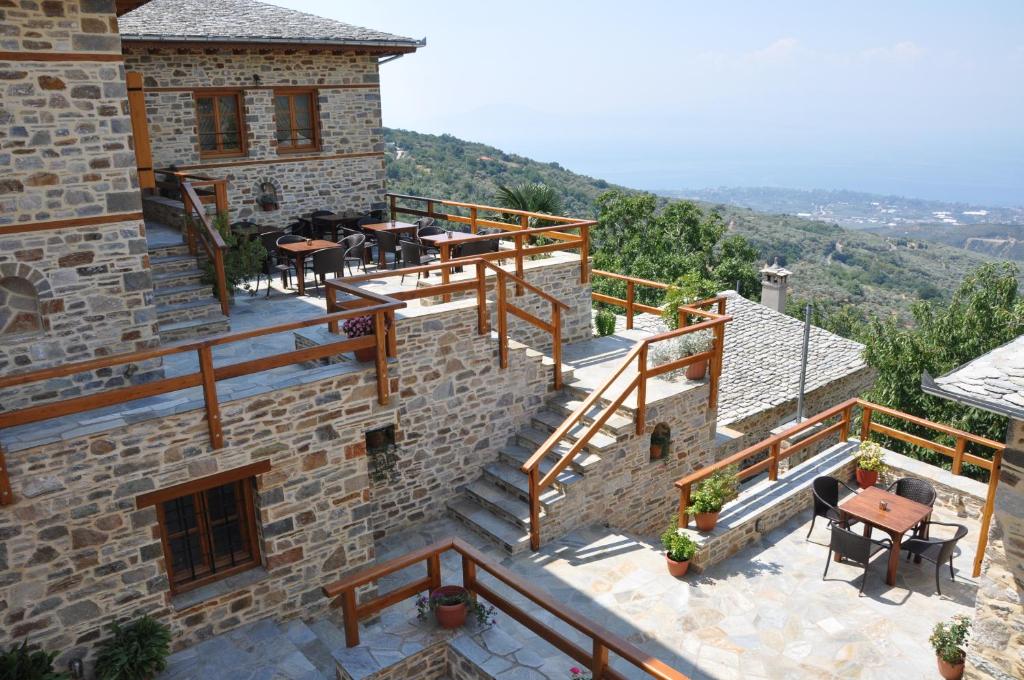 uma casa com uma varanda com mesas e cadeiras em Archontiko Koti em Agios Lavrentios