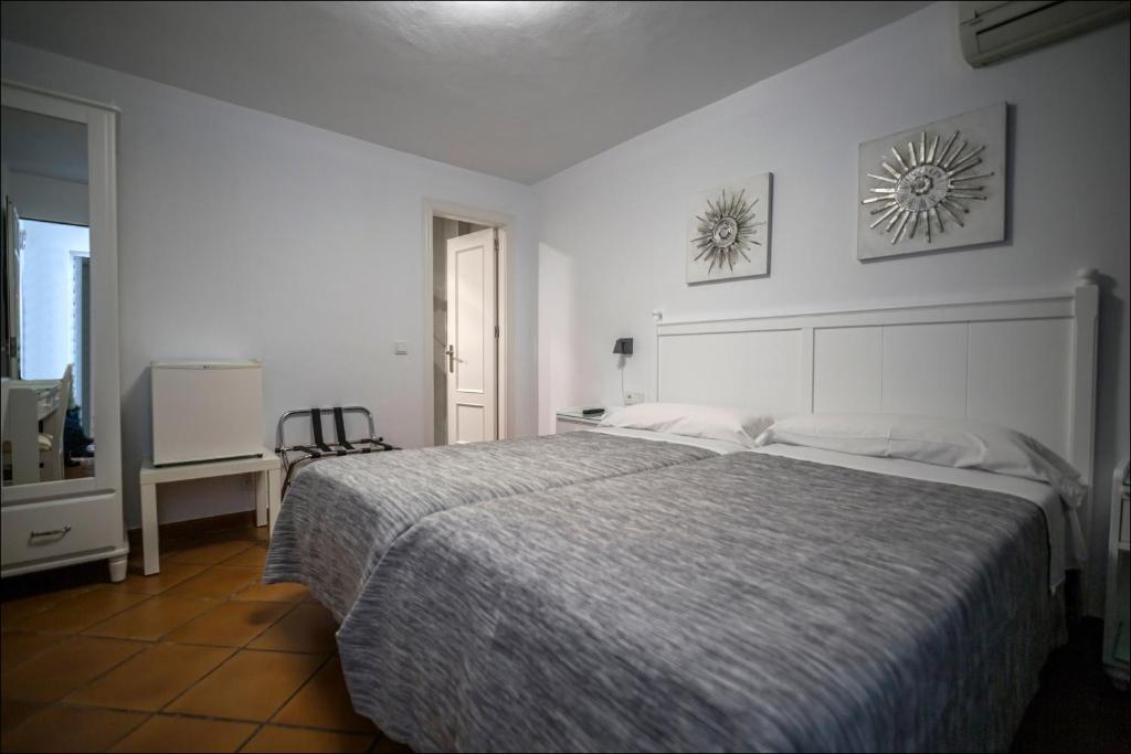 Habitación blanca con cama grande y escritorio. en Hostal San Ramón, en Marbella