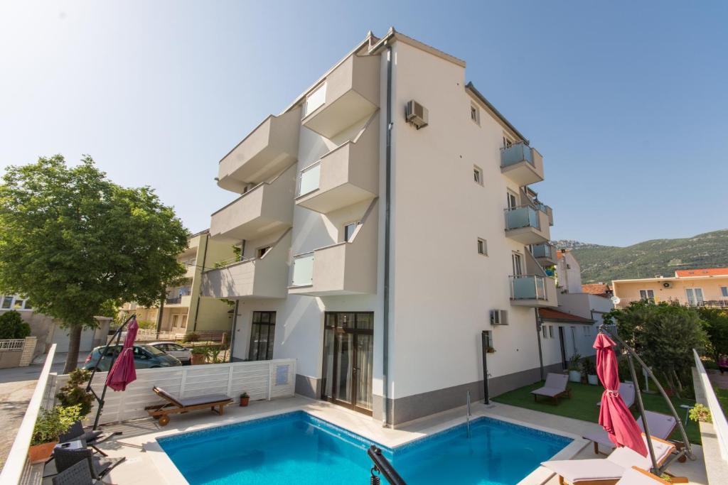 ein Gebäude mit einem Pool vor einem Gebäude in der Unterkunft Marko Apartments in Kaštela