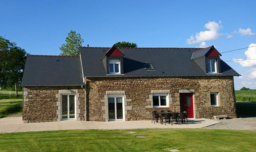 una gran casa de ladrillo con una puerta roja y sillas en Gîte de l'hamelinaie, en Montanel