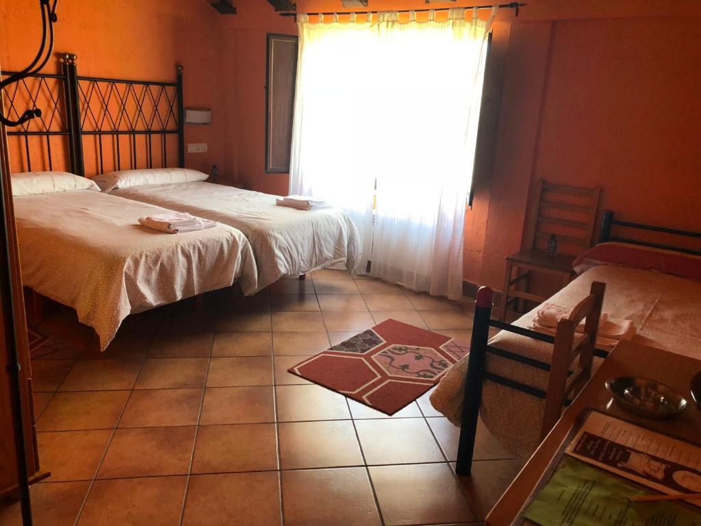 a bedroom with two beds and a window and a tile floor at Hotel CTR San Baudelio in Casillas de Berlanga