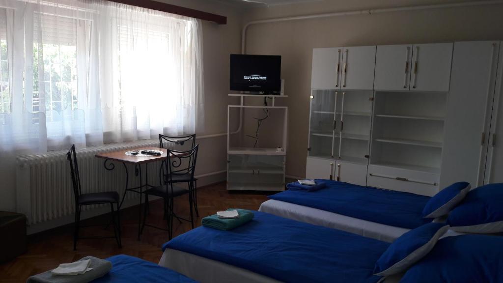 a hotel room with two beds and a table and a window at Peró Vendégház in Debrecen