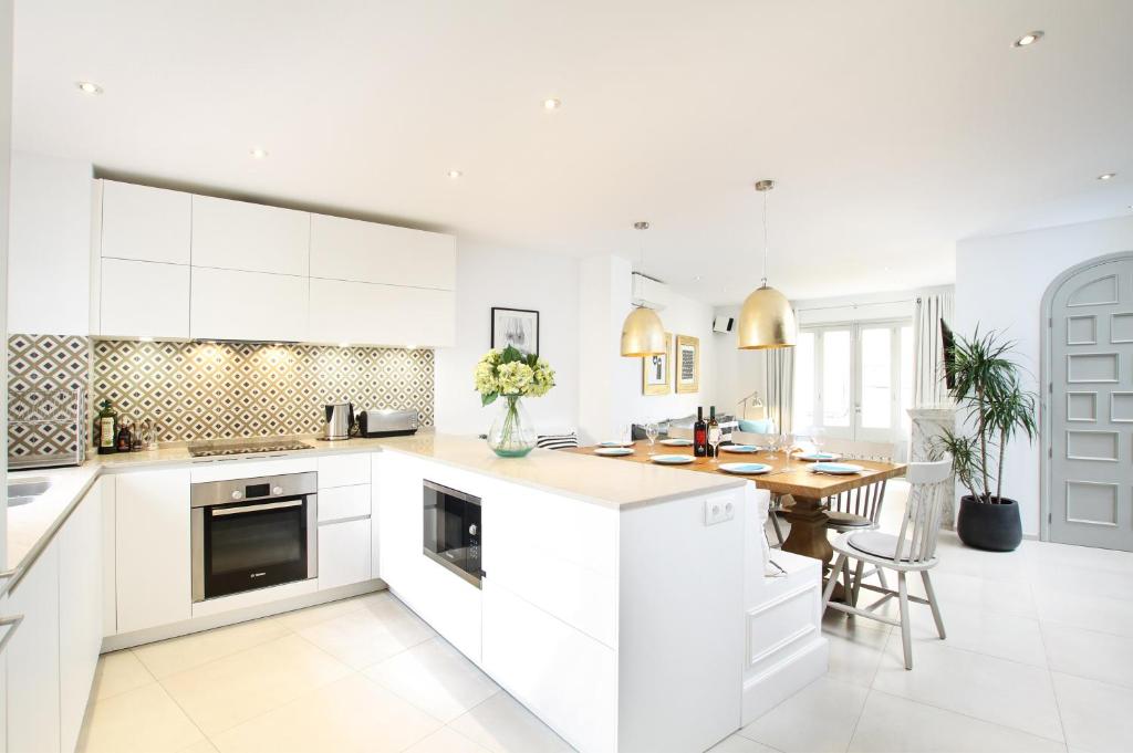 a kitchen with white cabinets and a wooden table at Casa Hugo in Pollença