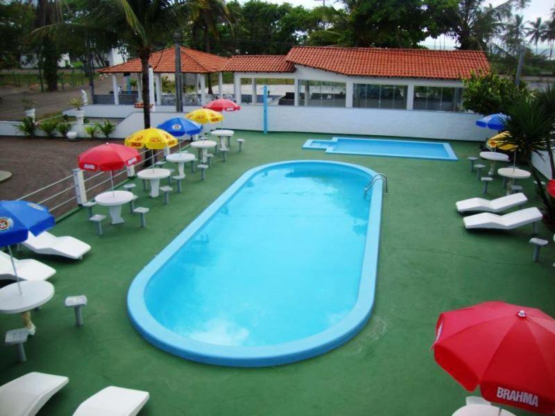 una piscina con sillas, sombrillas y sombrillas en Hotel Pousada Terras do Sem Fim, en Ilhéus