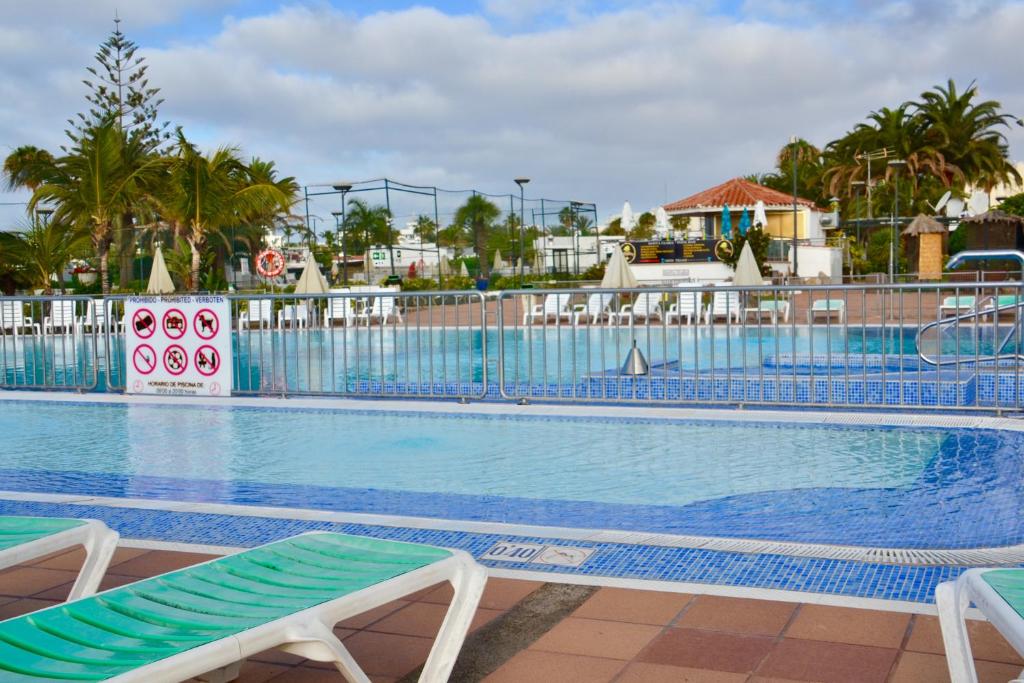 a swimming pool at a resort with two lounge chairs at Bungalow en Playa del Ingles in Playa del Ingles