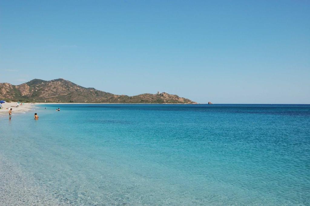 una playa con agua azul y gente en ella en Villetta Porto Corallo en Villaputzu