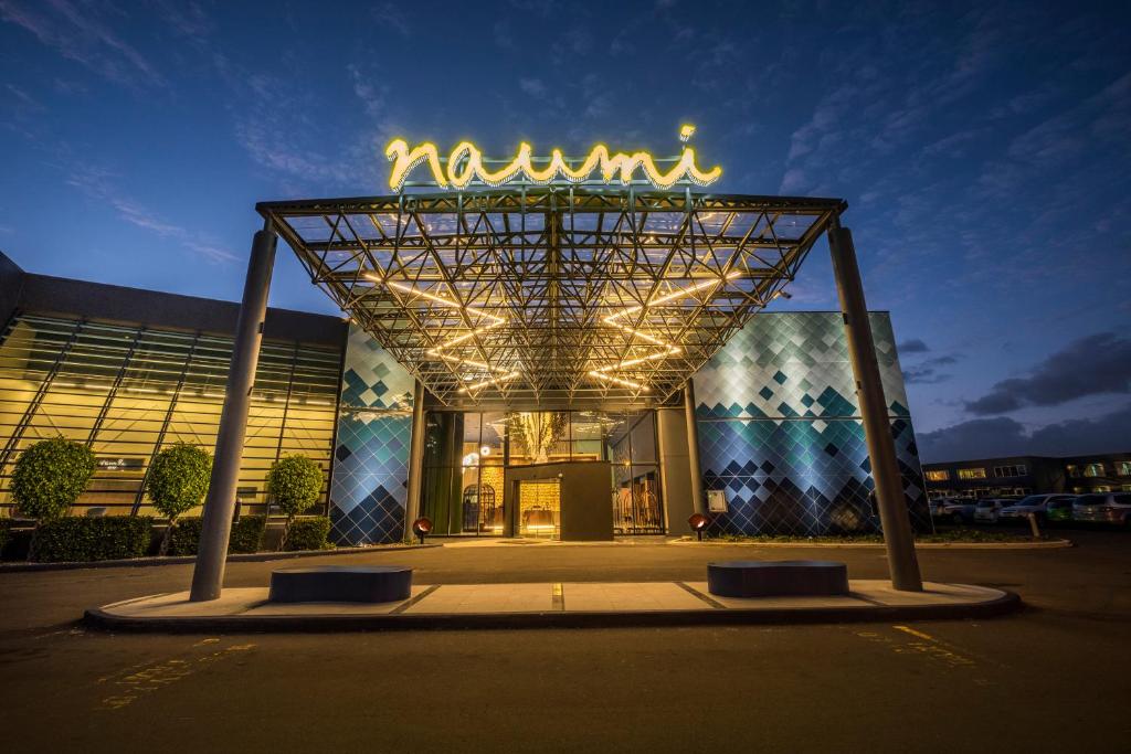 a building with a neon sign in front of it at Naumi Auckland Airport Hotel in Auckland