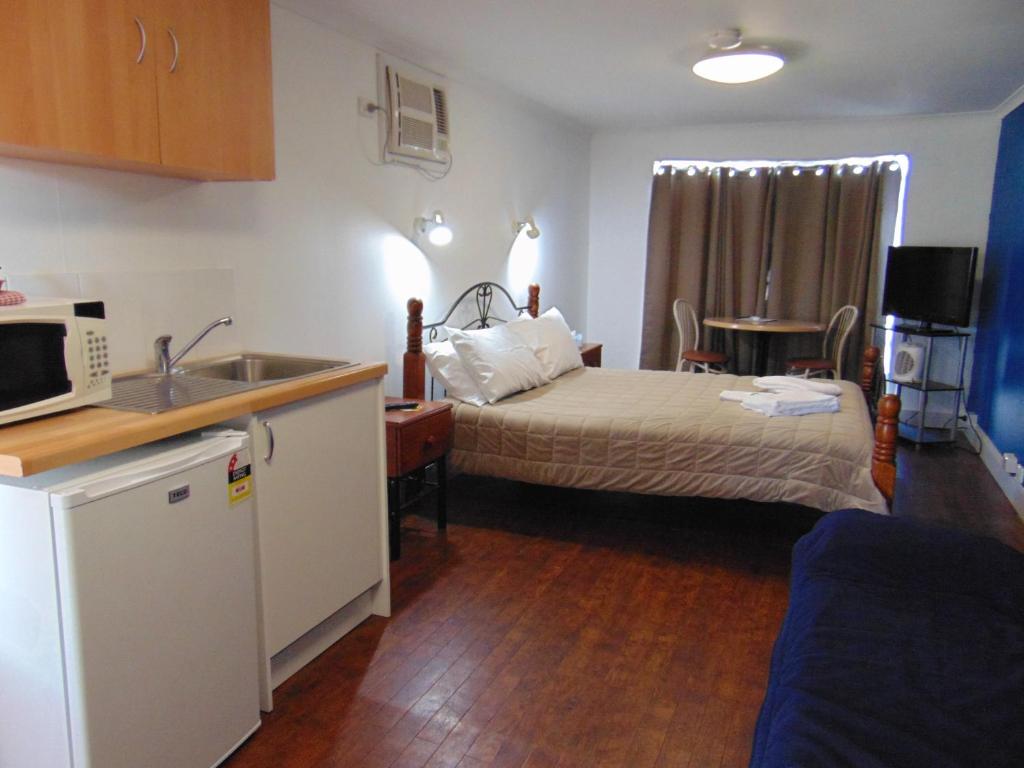 ein Schlafzimmer mit einem Bett und eine Küche mit einem Waschbecken in der Unterkunft Fremantle Village in Fremantle