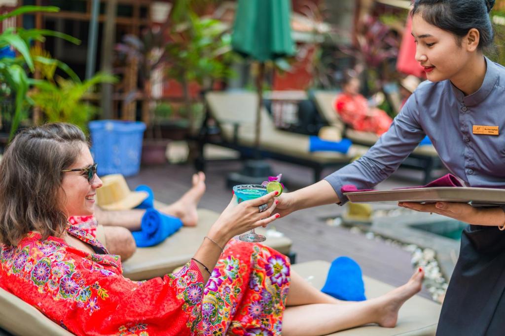 Una mujer le está dando a una mujer un trago. en Mekong Angkor Palace Inn, en Siem Reap