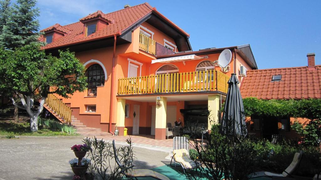 an orange house with a balcony and an umbrella at Villa Alexandr in Alsópáhok