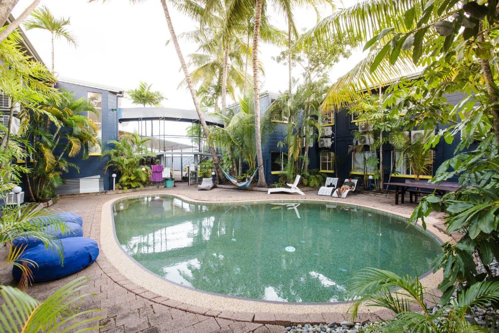 a large swimming pool in a courtyard with palm trees at Mad Monkey Village in Cairns