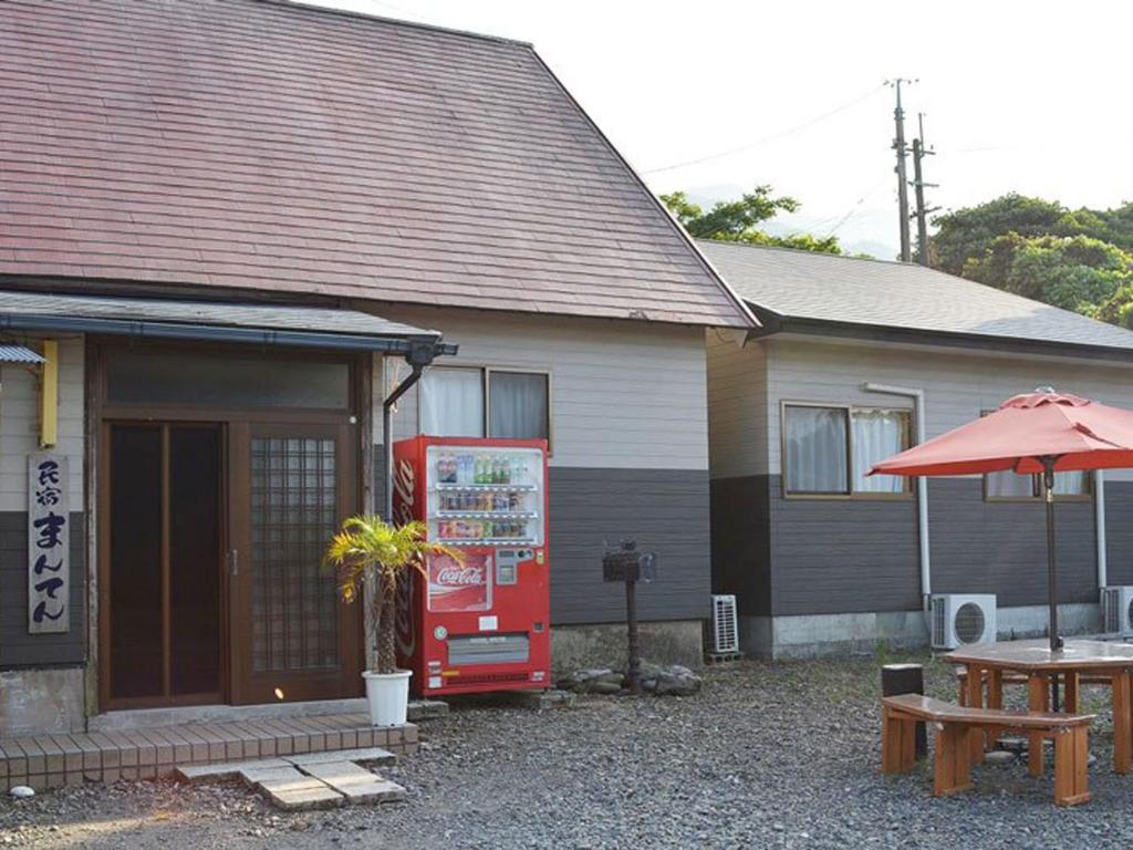 a building with a red vending machine next to a table at Minshuku Manten in Yakushima