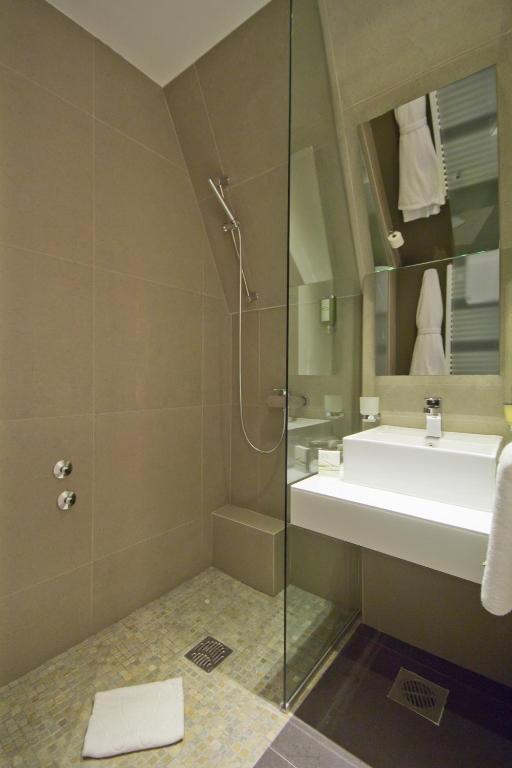 um banheiro com chuveiro, pia e espelho em Hotel Sole em Niš