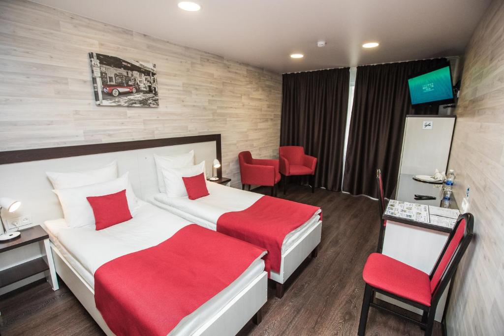 a hotel room with two beds and red chairs at City Fox Hotel in Barnaul