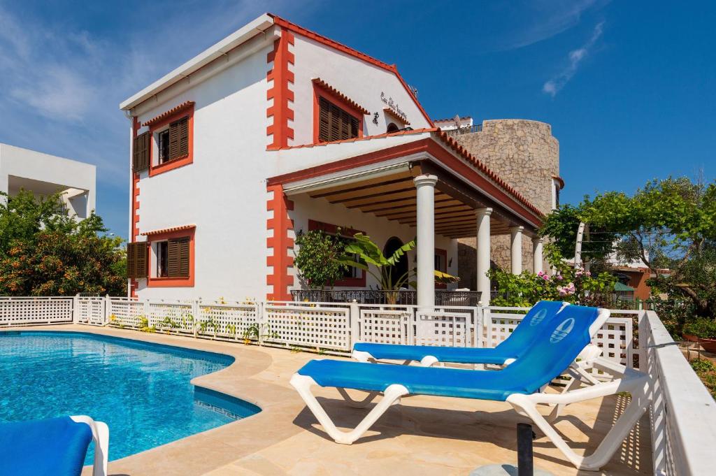 a villa with a swimming pool and two lounge chairs at Villa Tortugas, 5 min ibiza City in Ibiza Town