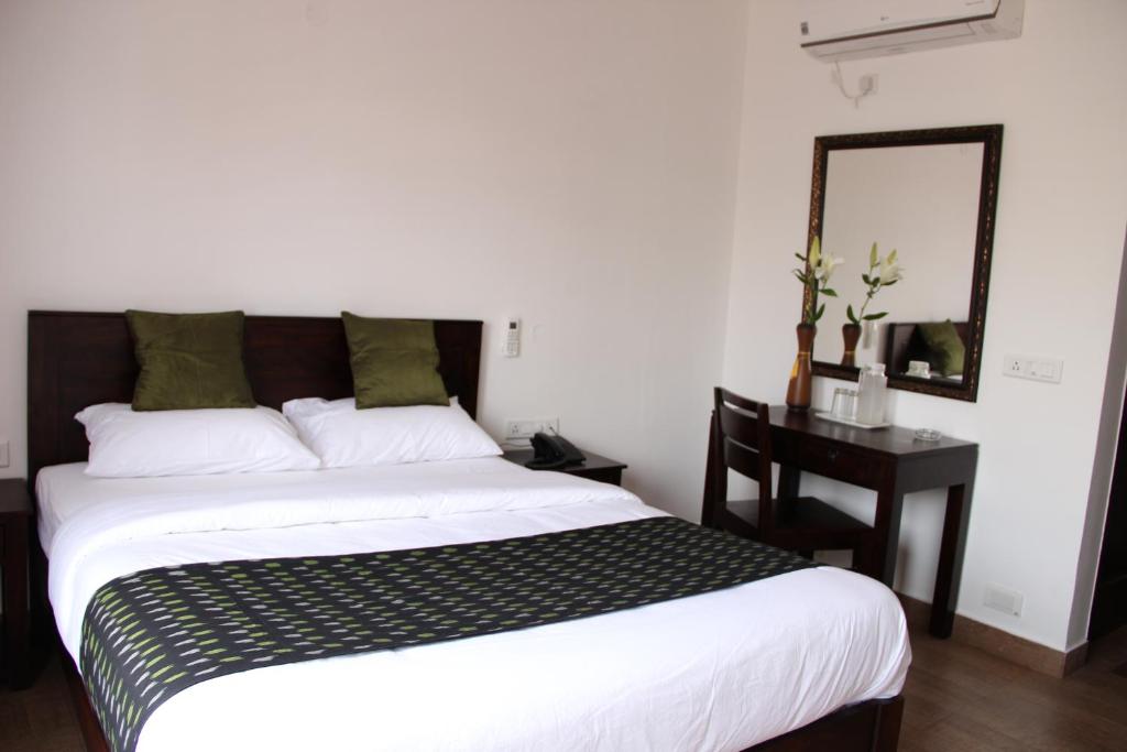 a bedroom with a bed and a desk and a mirror at Thyme the Transit in Bangalore