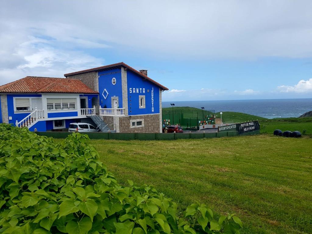 a blue house on a hill next to the ocean at Apartamentos Santa Justa in Ubiarco