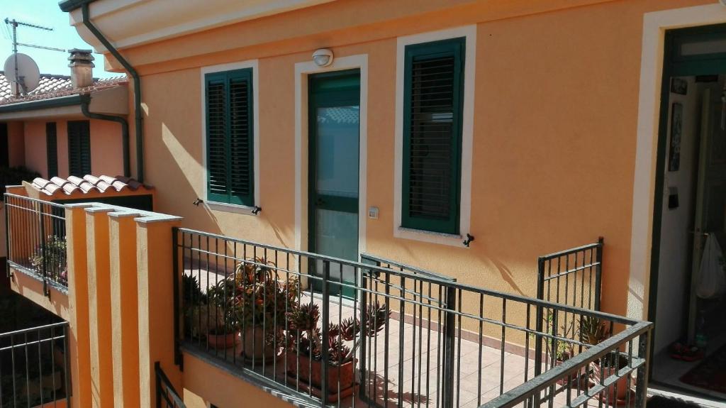 ein orangefarbenes Gebäude mit grünen Rollläden und einem Balkon in der Unterkunft Appartamento in paese a Santa Teresa in Santa Teresa Gallura