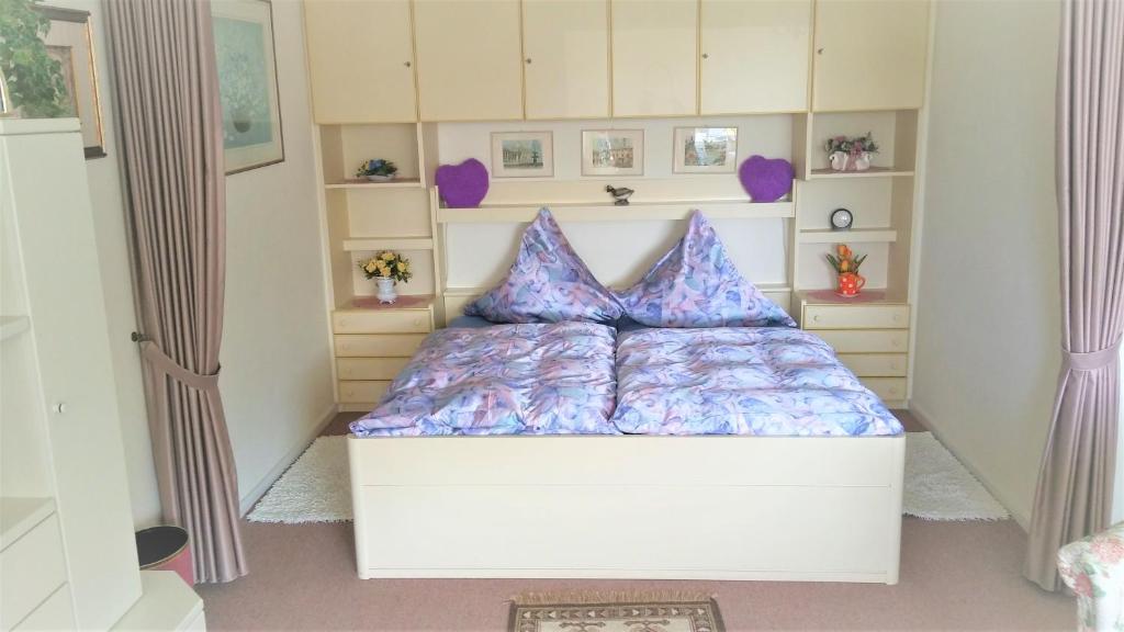 ein Schlafzimmer mit einem weißen Bett mit lila Kissen in der Unterkunft Apartment Seaside in Westerland