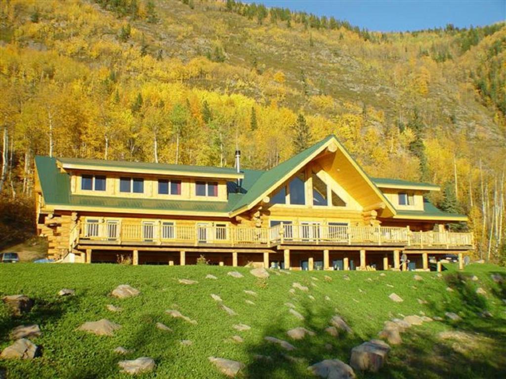 a large yellow house with a green roof at Williston Lake Resort in Hudson Hope