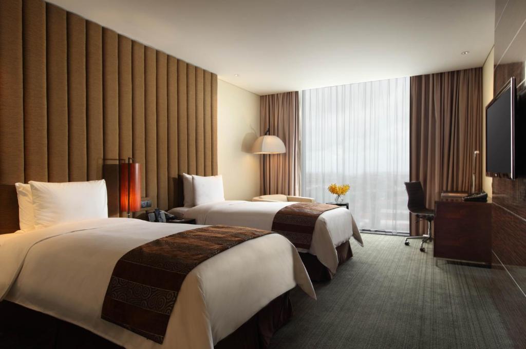 a hotel room with two beds and a television at PO Hotel Semarang in Semarang