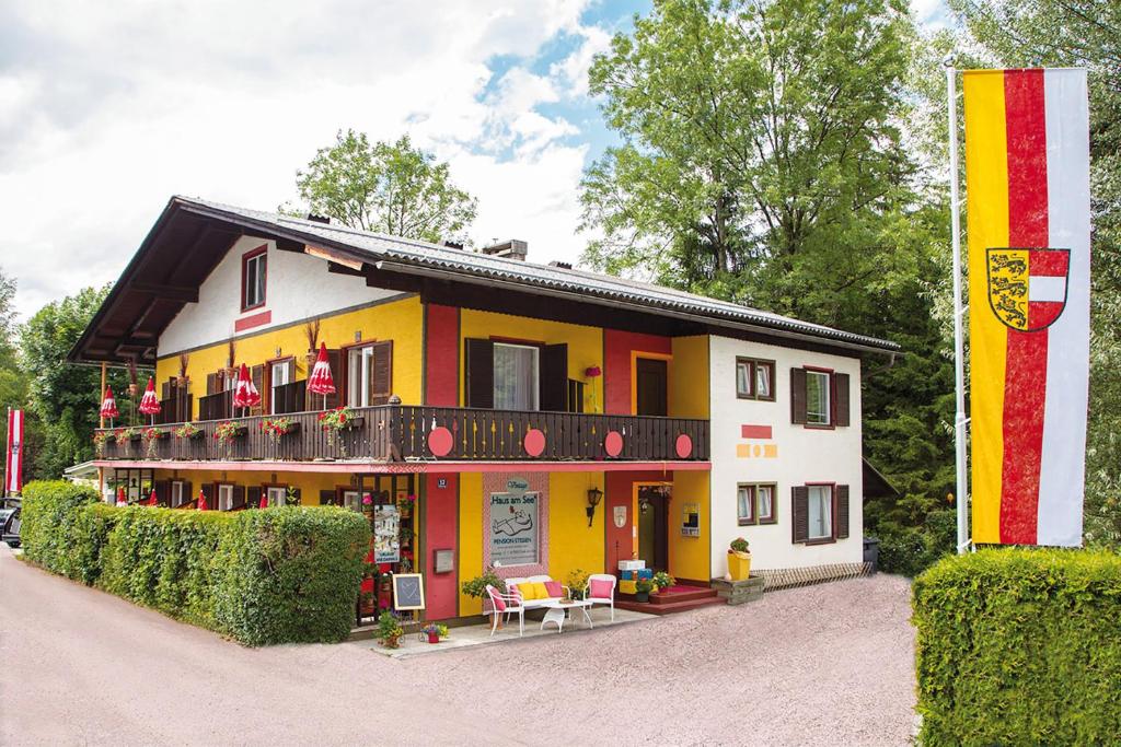 ein gelbes und weißes Gebäude mit einem Balkon in der Unterkunft Pension Stissen Haus am See in Faak am See