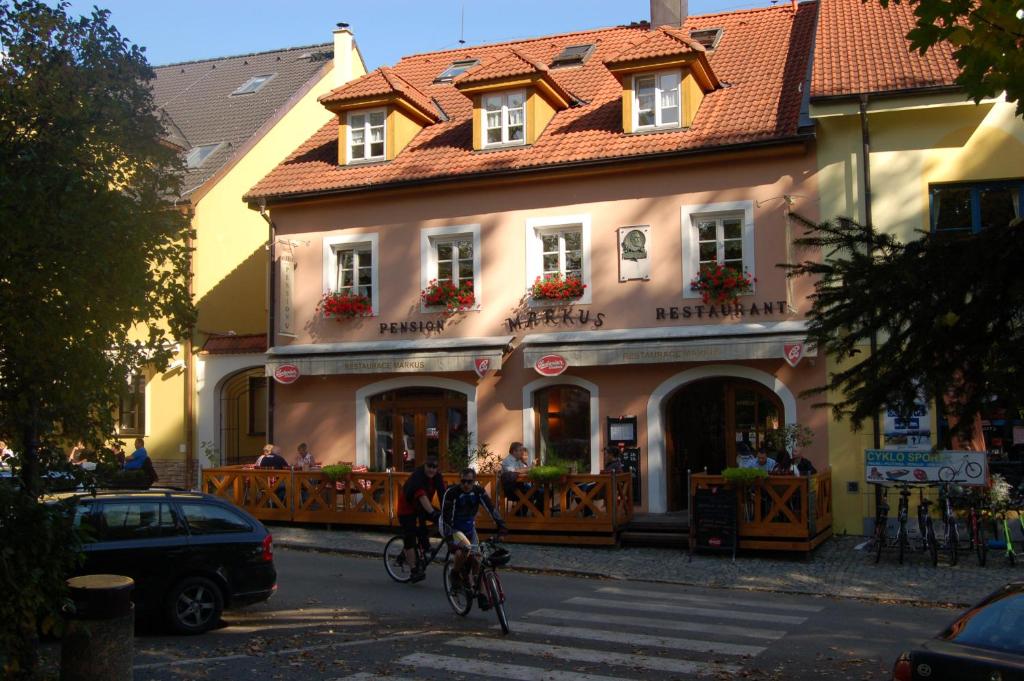 zwei Personen, die vor einem Gebäude Fahrrad fahren in der Unterkunft Penzion Markus in Frymburk