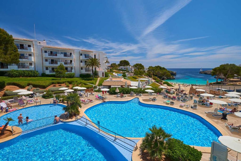 a beach with a pool, chairs, and a pool table at Inturotel Esmeralda Park in Cala d´Or